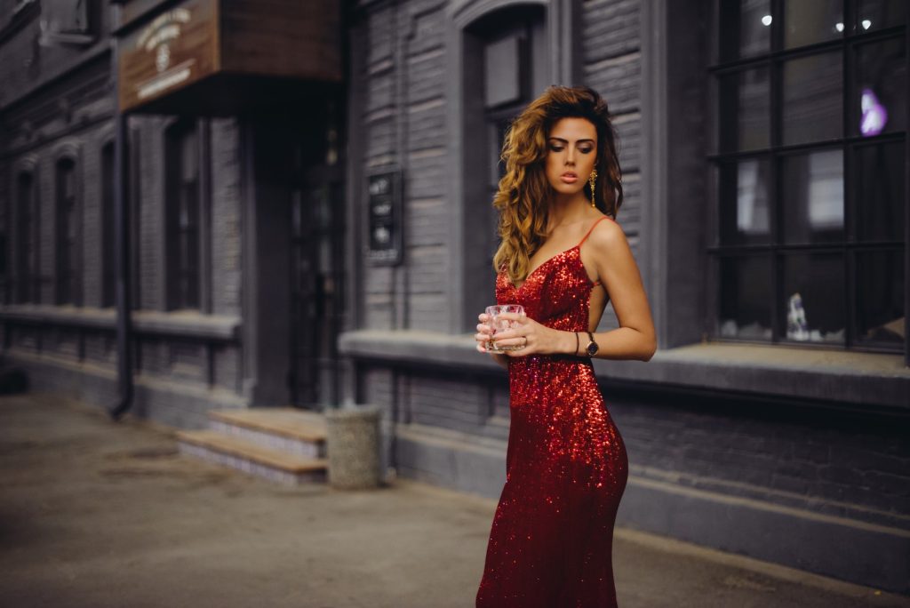 femme en robe rouge à bretelles spaghetti debout sur la route pendant la journée