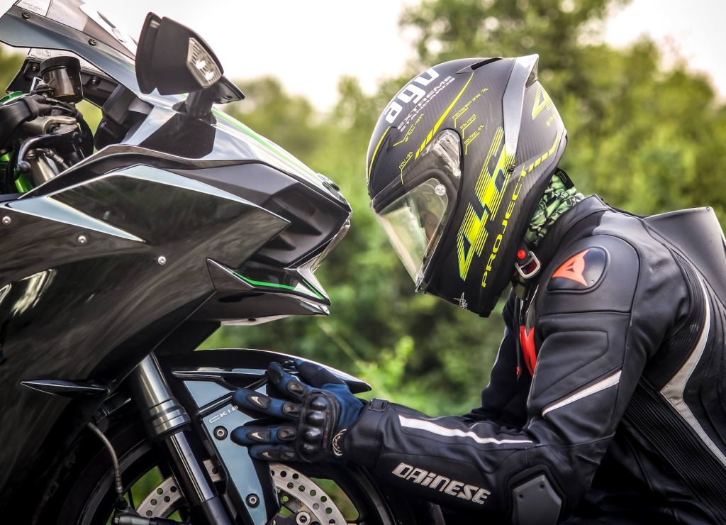 personne portant un casque en tenant un motocycle