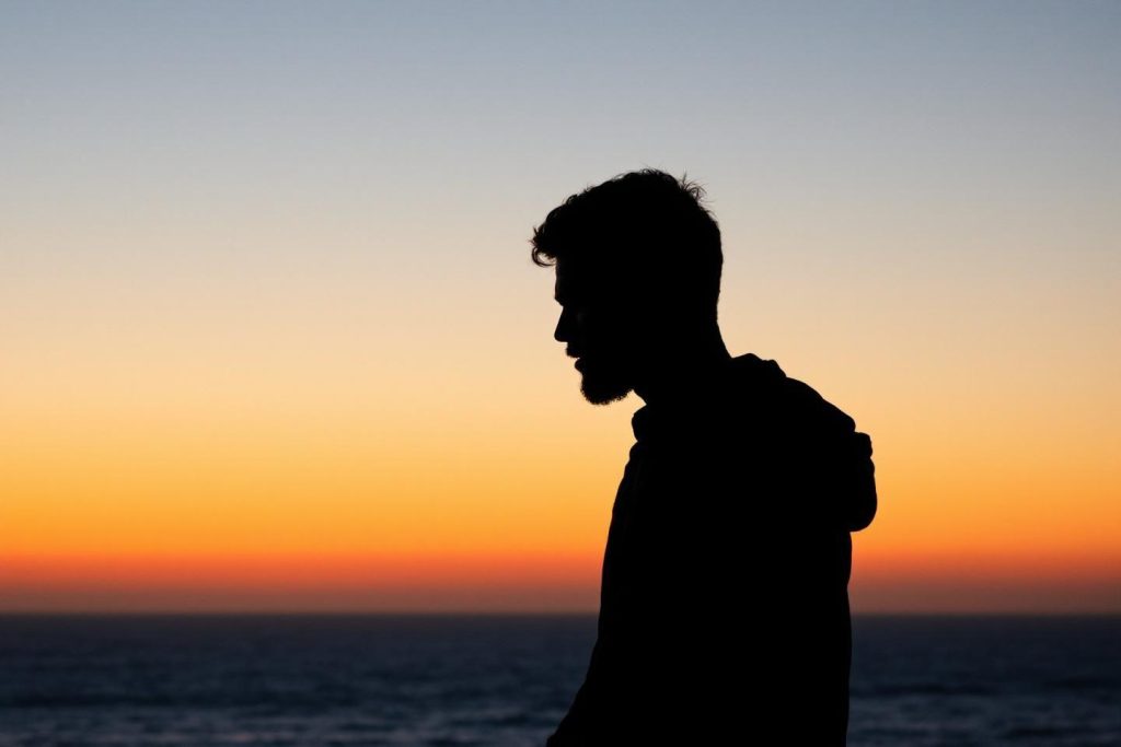Silhouette d'une personne face à l'horizon lors d'un coucher de soleil