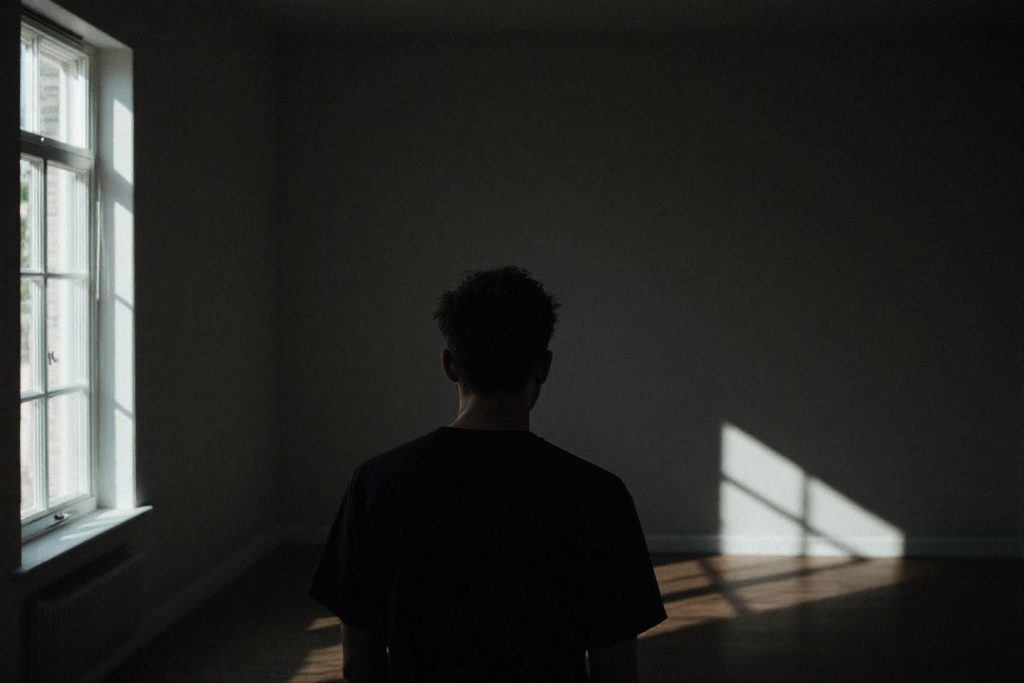 Silhouette dos à la fenêtre dans une pièce sombre