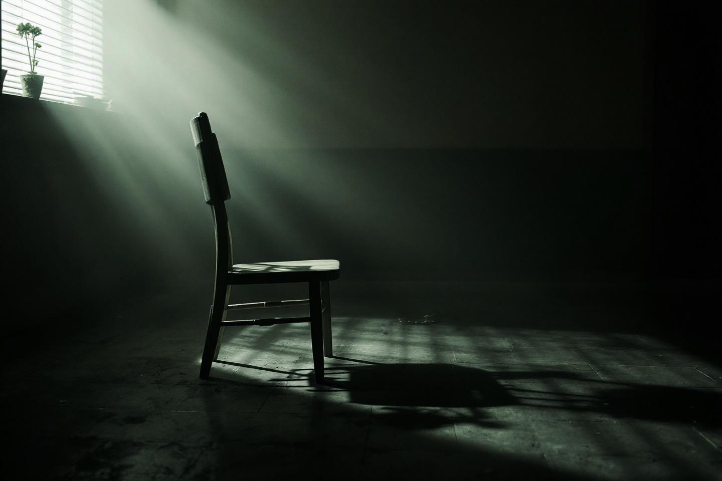 Chaise isolée dans une pièce sombre avec rayon lumineux