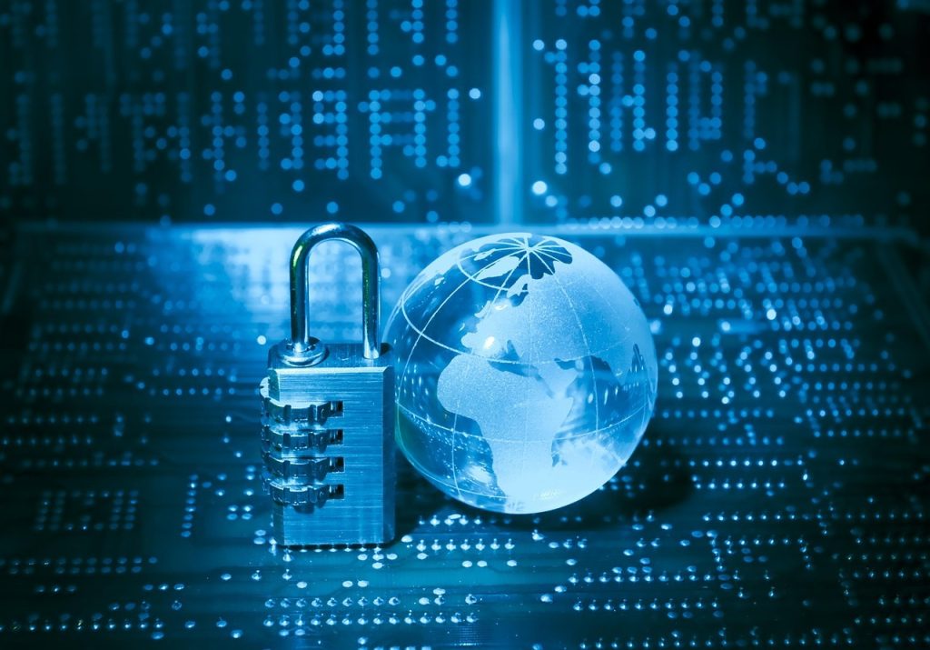 Un cadenas à combinaison et un globe de verre sont posés sur un circuit imprimé numérique, symbolisant la cybersécurité mondiale et la protection des données.