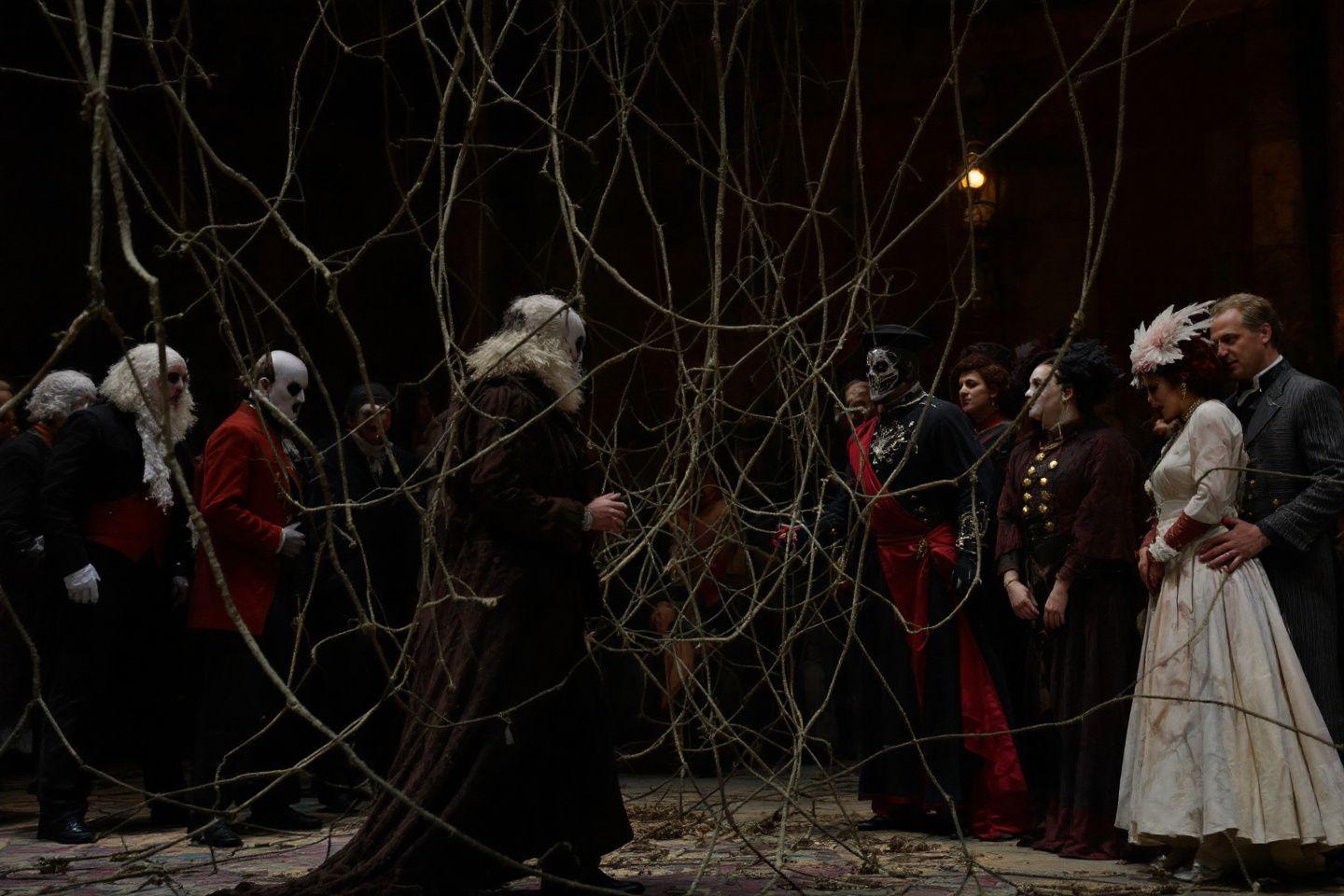 Scène théâtrale sombre avec personnages en costumes stylisés