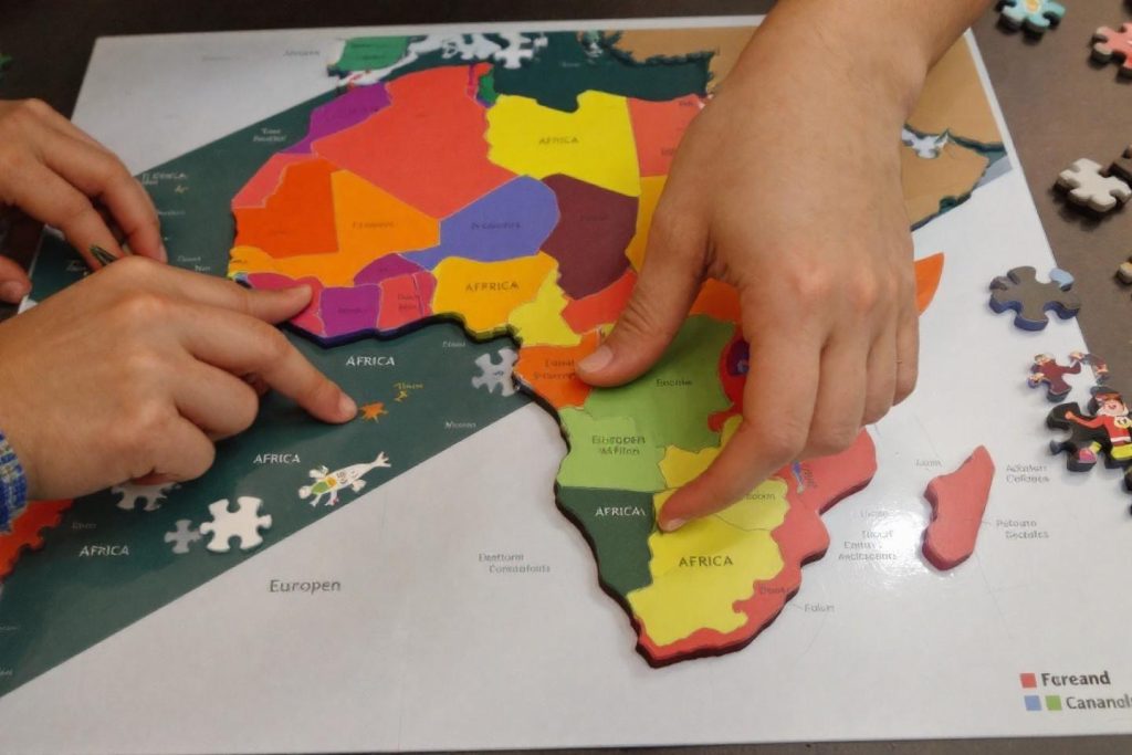 Mains assemblant un puzzle géographique coloré de l'Afrique