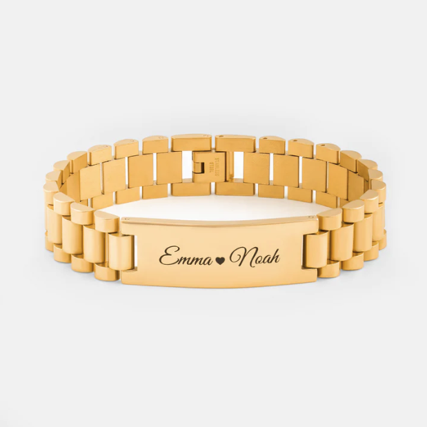 Bracelet à maillons en or avec les noms "Emma" et "Noah" gravés sur une plaque rectangulaire, séparés par un petit symbole de cœur.