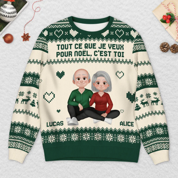 Un pull vert et blanc avec des images de dessins animés d'un couple âgé, étiqueté "Lucas" et "Alice", et le texte français "Tout ce que je veux pour Noël, c'est toi".