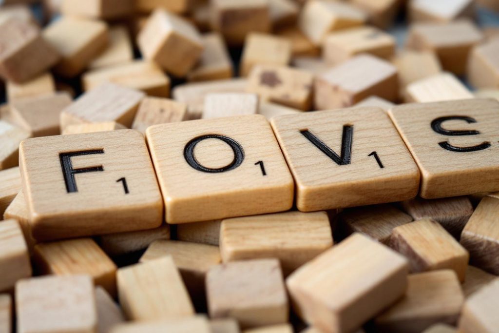 Tuiles en bois de Scrabble dispersées avec le mot Fovs au centre
