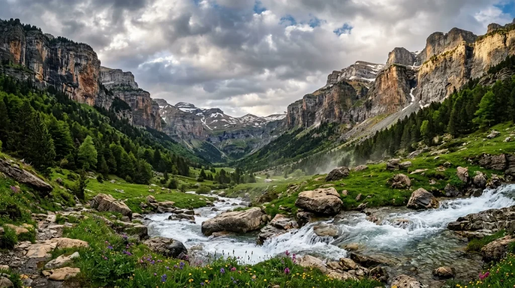 Vallée alpine avec torrent, prairies vertes et pics rocheux enneigés